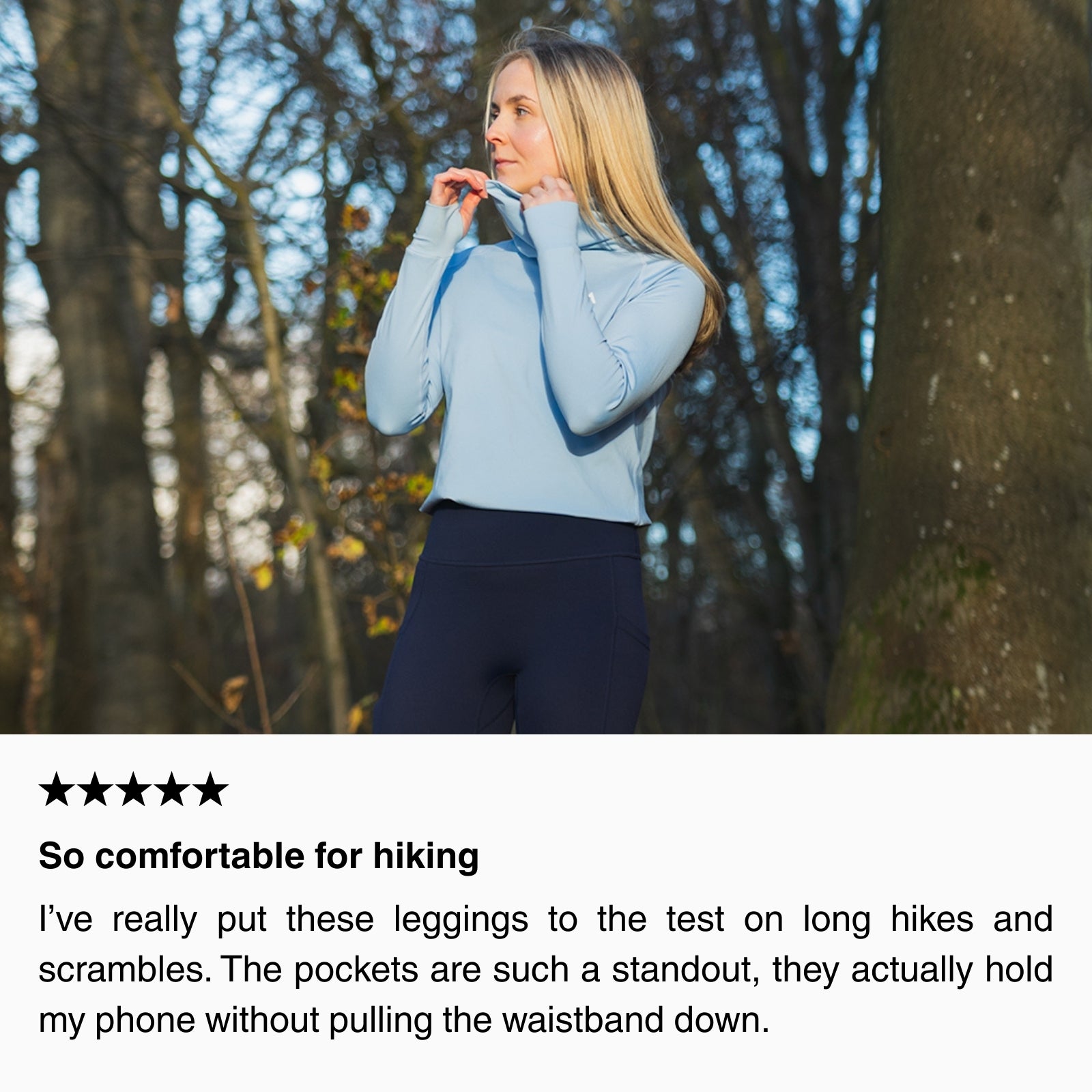 Woman wearing a long-sleeve hiking base layer adjusting the collar in a woodland setting, showing a comfortable, close-fitting layer designed for long hikes.