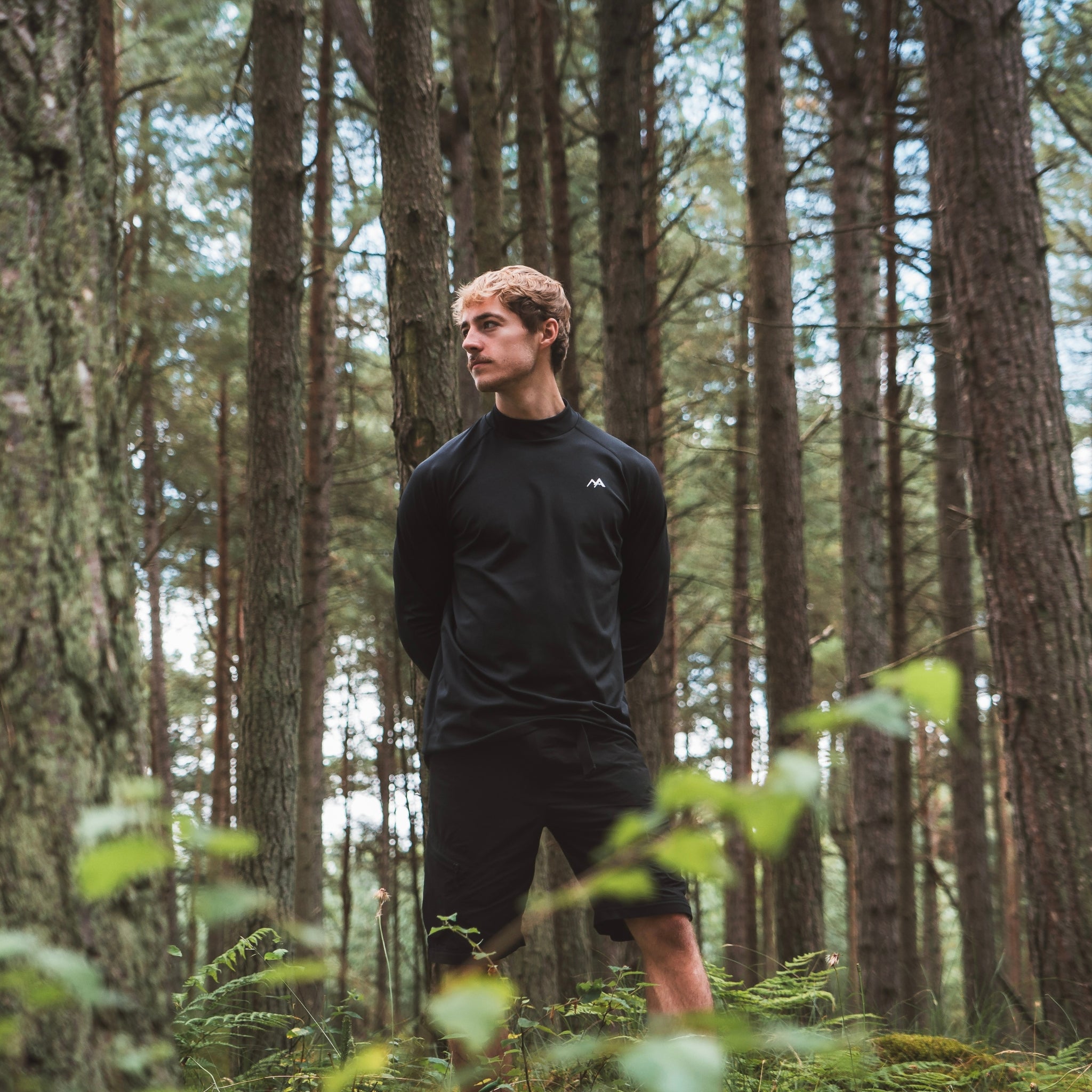 Male wearing Arctic Eco-Sno Men's Black Base Layer Top in forest