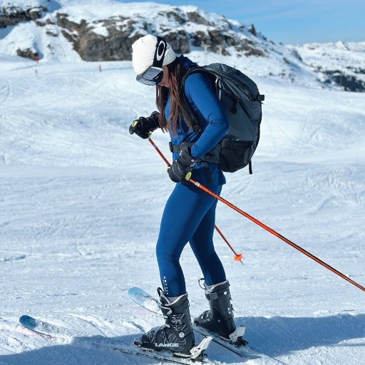 Women skiing in the snow wearing blue base layers.