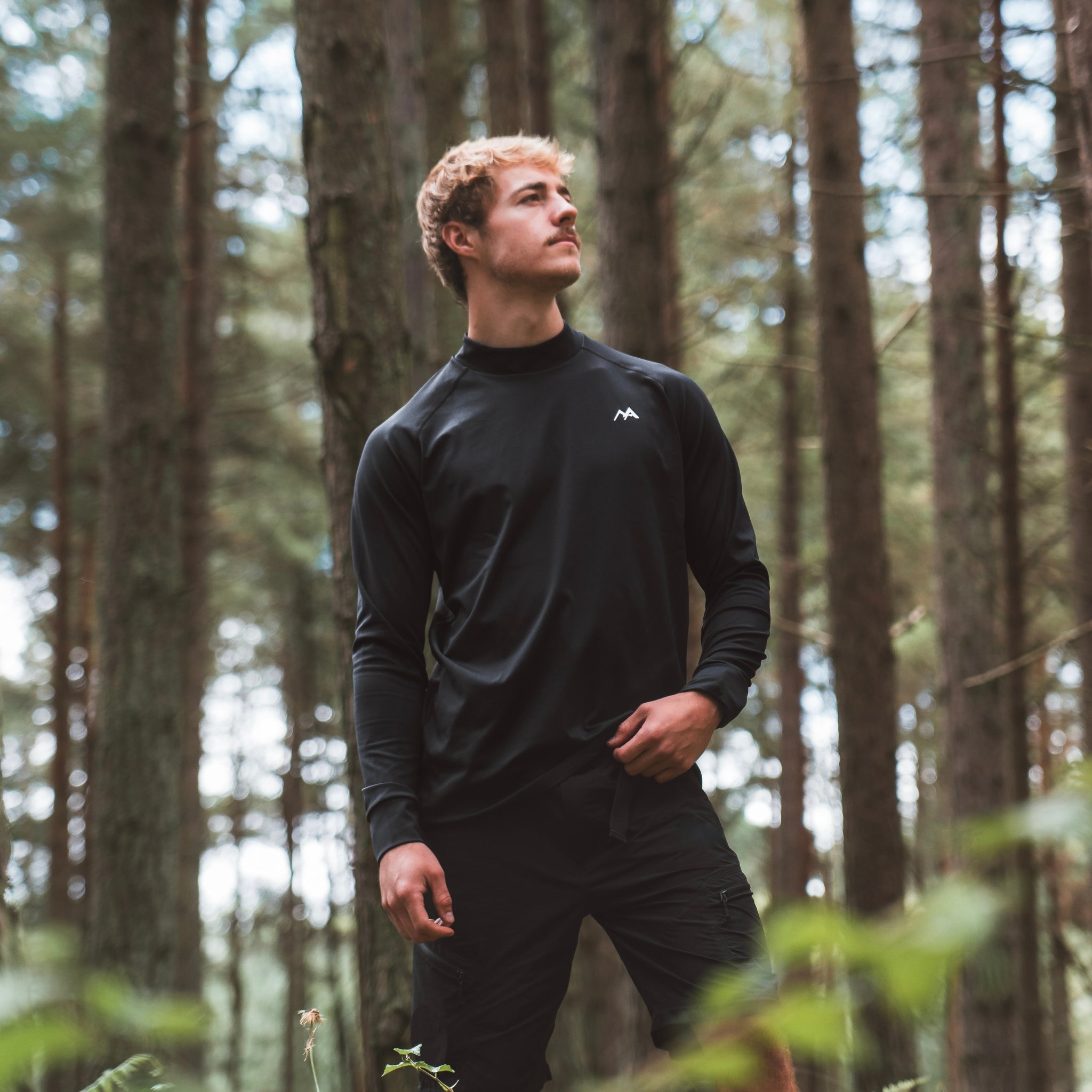 Male wearing Arctic Eco-Sno Men's Black Base Layer Top in forest