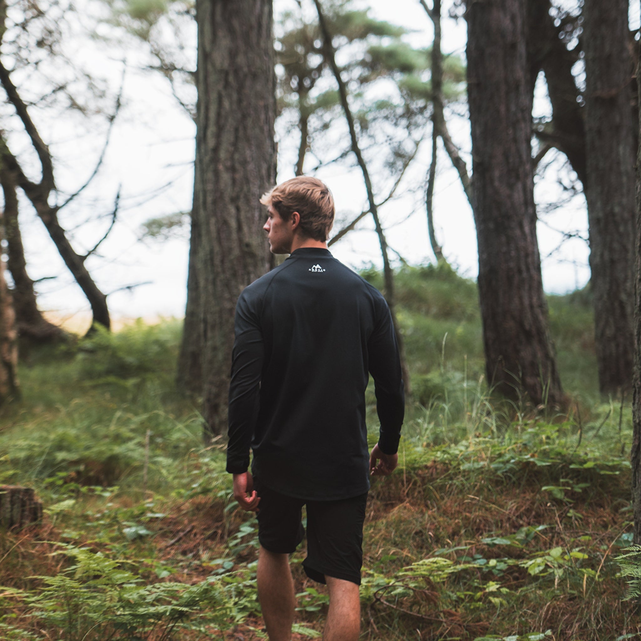 Male wearing Arctic Eco-Sno Men's Black Base Layer Top in forest