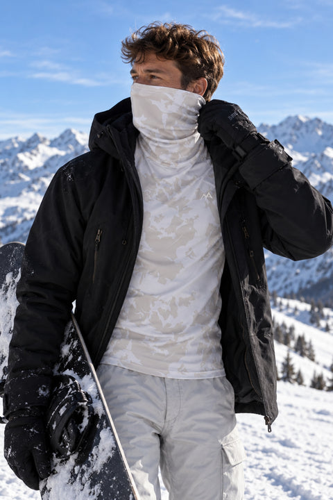 Man wearing Arctic Eco-Sno men's Alpine Grey thermal ski base layer top with built-in neck warmer pulled over his face, under an open black snowboard jacket in the snowy Alps.