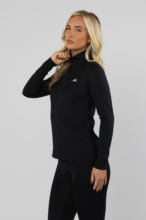 Side profile of a woman wearing the Arctic Eco-Sno black quarter zip thermal base layer top, showing the fitted silhouette and high collar.