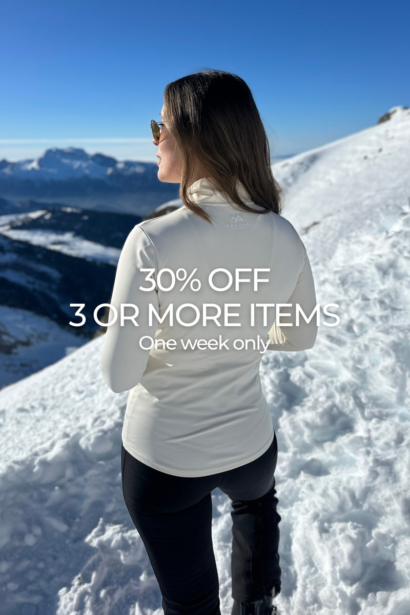 Woman wearing cream base layer in snowy landscape with text on screen advertising 30% off sale