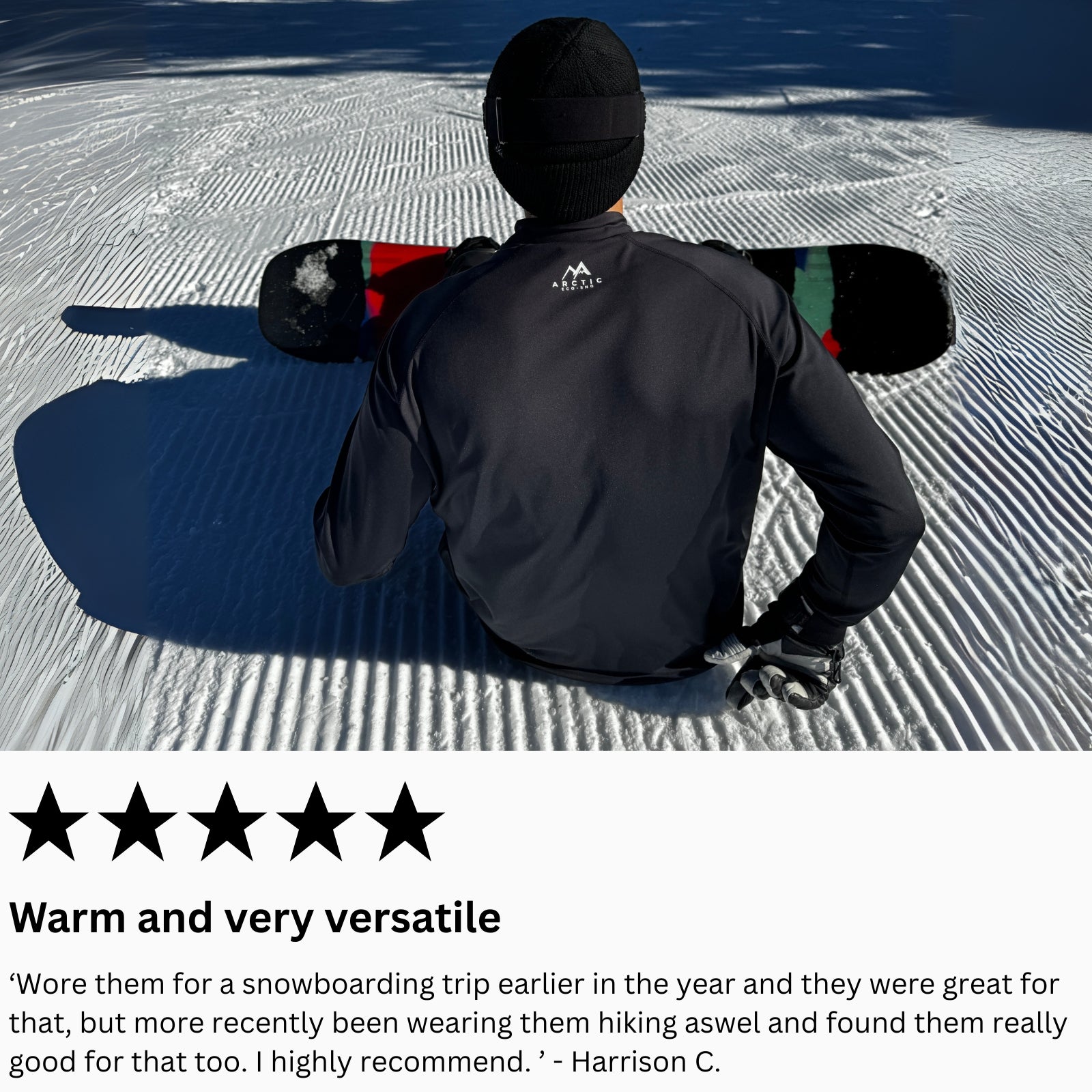 man sitting on a snowy slope with a snowboard, wearing a black arctic eco sno base layer top.