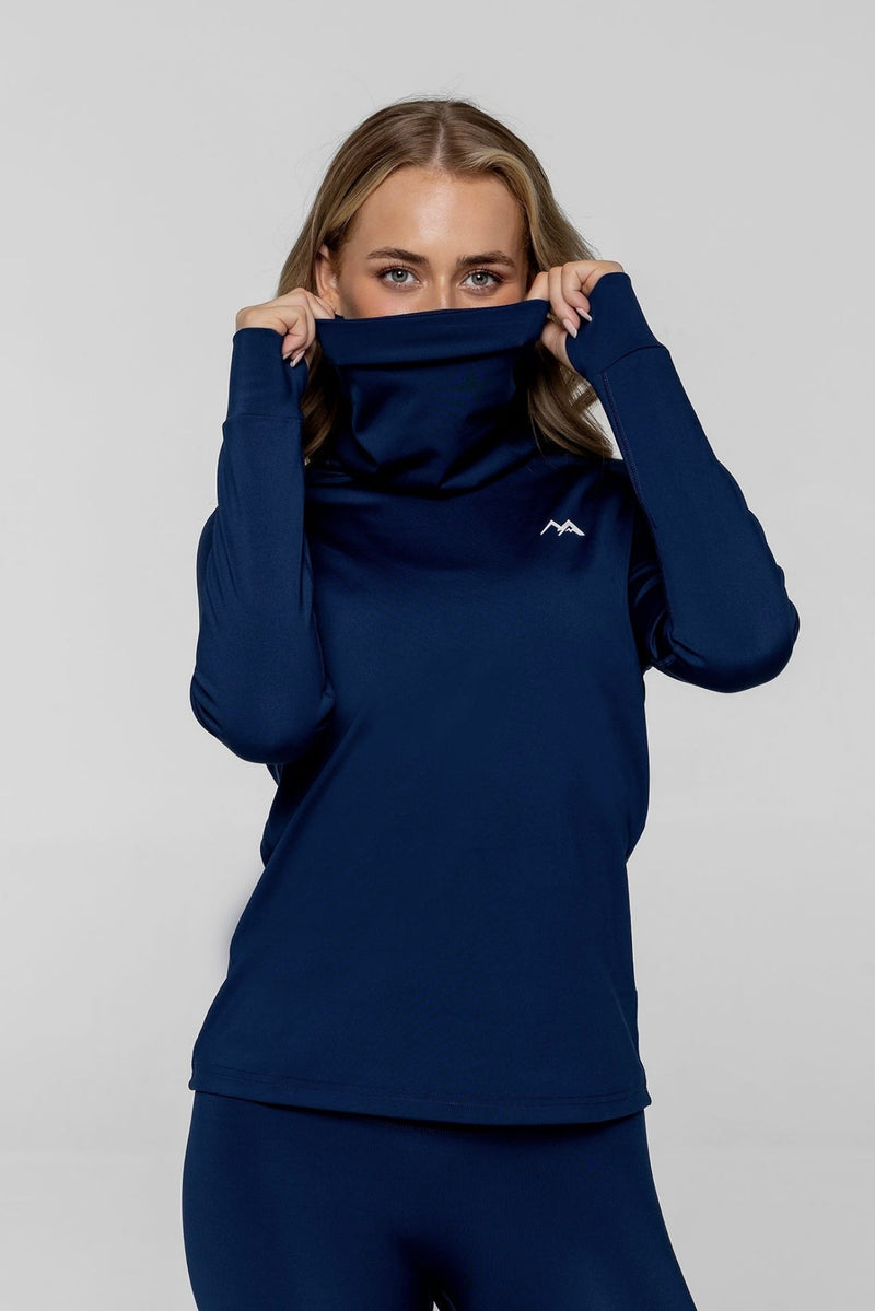 Woman wearing arctic eco sno navy thermal base layer top showing face and neckwarmer with grey background.